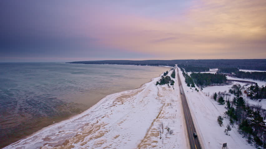 Drone flyover of snowy wilderness in northern Michigan with US Highway 2 leading toward Lake Superior