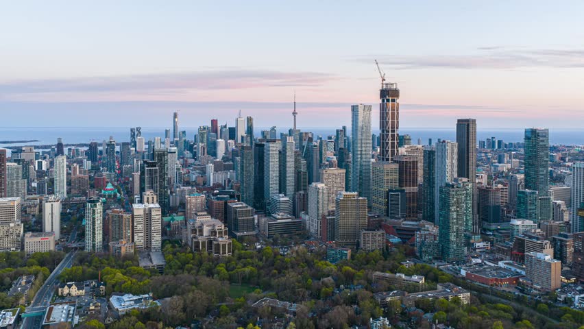 Dynamic sunset to night hyperlapse over downtown Toronto, illuminated urban skyline, busy streets, modern skyscrapers, Lake Ontario in distance