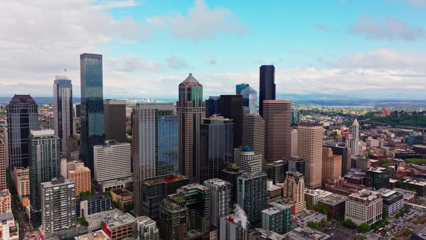 Dynamic drone shot of Seattle metropolitan area featuring Smith Tower and Columbia Center buildings. Cinematic footage showcasing Pacific Northwest urban architecture and city streets below.