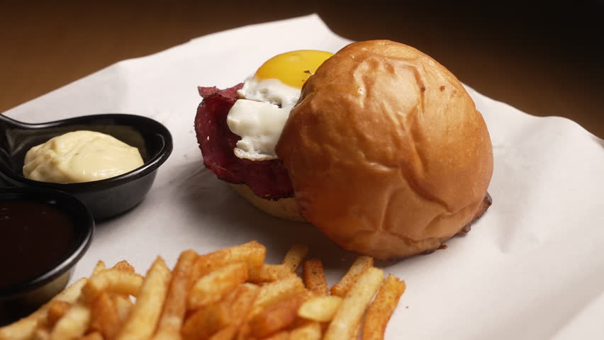 Appetizing burger with bacon, a fried egg, and french fries served on a platter, fa01