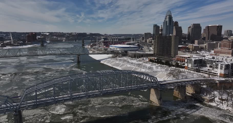 Aerial view of the Cincinnati skyline with skyscrapers and bridges crossing the frozen Ohio River with ice floes under a blue sky Cincinnati, Ohio, United States.