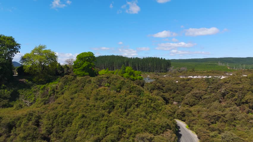 Panoramic aerial view of New Zealand nature with scrub and forest, surrounded by man made pine forestry farms.