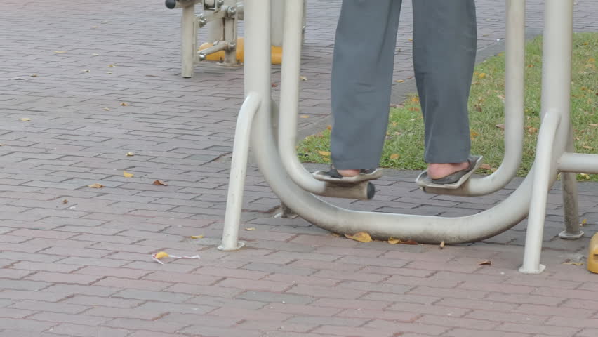 Close up of an elderly person legs exercising on an outdoor air walker machine in a city park, senior fitness and healthy aging concept, 4k prores