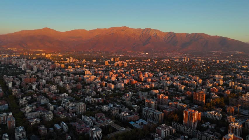 Aerial view of santiago, the capital of chile, with the majestic andes mountain range in the background illuminated by the golden sunset light