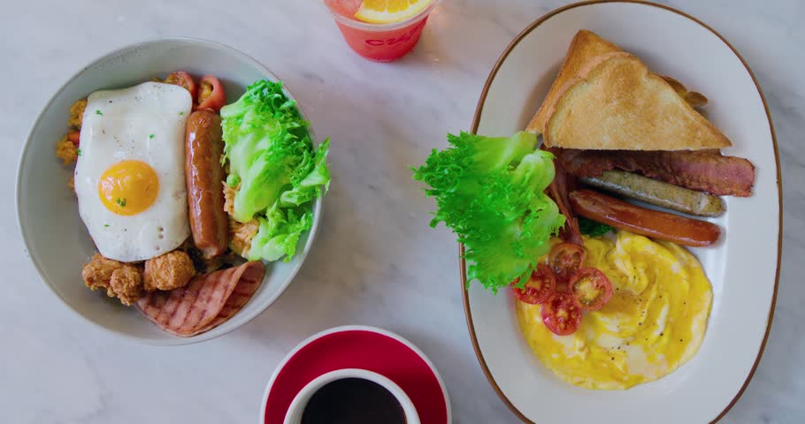 Two hearty breakfast plates with eggs, sausages, bacon, and toast served on a bright marble table. Delicious morning meal concept. Fresh, vibrant, and appetizing food photography.