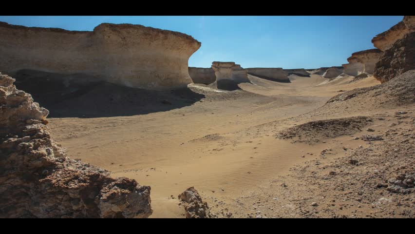 Cinematic traveling shot through rocky desert canyon in Zekret Qatar with dramatic shadows, sand formations and eroded limestone cliffs
