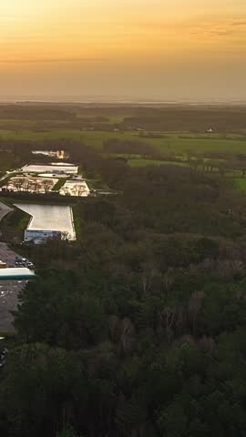 Aerial time lapse of industrial facility by river at sunset with surrounding fields