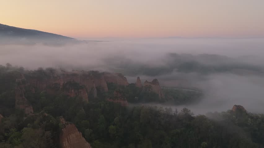 Aerial view of the Valdarno rock formations shrouded in thick morning fog and soft sunrise light over the Tuscan landscape in Florence, Tuscany, Italy.