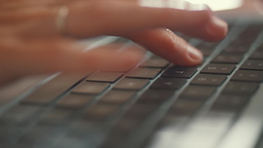 Close-up of female fingers quickly typing a message on a modern notebook keyboard