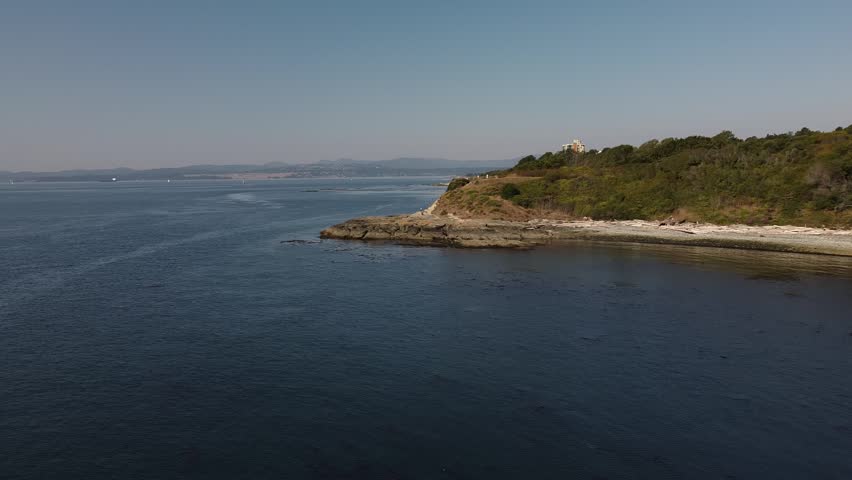 Breathtaking aerial drone footage of the rugged coastline on Vancouver Island near Victoria, British Columbia. The shot captures the pristine blue waters of the Pacific Ocean meeting the rocky shoreline and lush greenery. Perfect for travel documentaries, real estate promotions, and environmental storytelling showcasing the natural beauty of Western Canada.