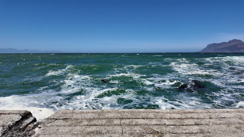 Rough sea waves crashing on pier in Kalk Bay, South Africa. 
