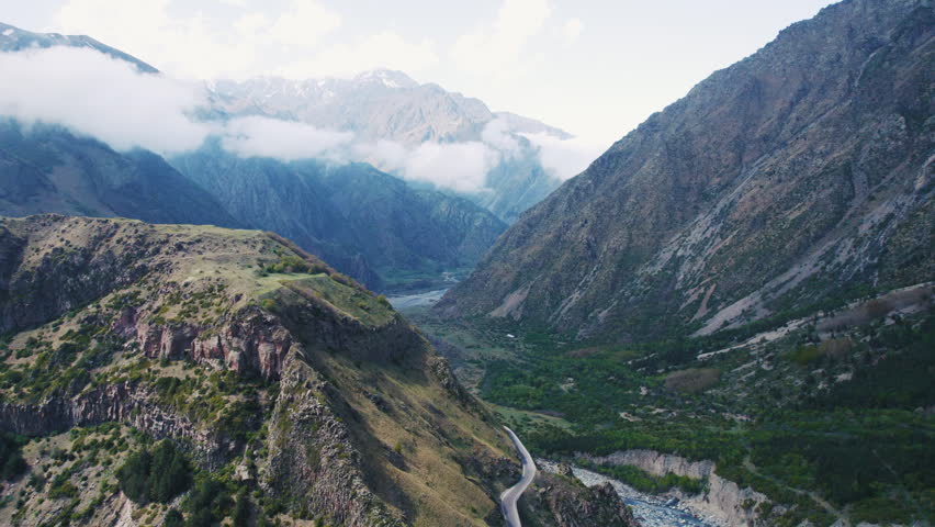 Aerial view of a stunning mountain valley with river and clouds