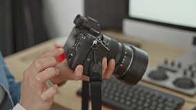 Woman adjusts camera dial with fingers while holding a mirrorless lens near keyboard and monitor in studio; focus creativity craft. - Powered by Shutterstock - Get 15% off with code: PIKWIZARD15
