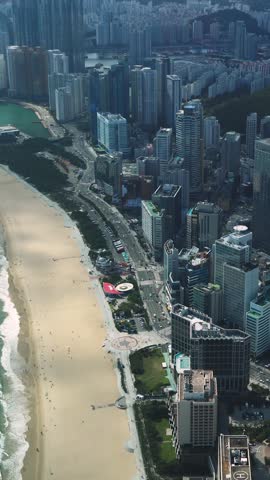 Haeundae beach, Busan, South Korea, aerial view with Busan bay, Songnim Park, Haeundae-gu district, white sand beach promenade, sea with Dongbaekseom Island, Gwangan bridge and Busan skyline panorama