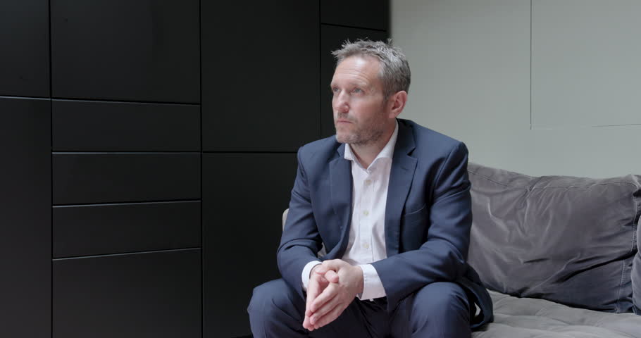 Portrait of Mature Businessman Looking at camera, sitting on Sofa in Corporate Office wearing Suit