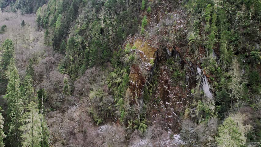 Rugged vertical mountain terrain in the Eastern Himalayas, showcasing primordial stone cliffs and alpine vegetation in a remote Tibetan wilderness.