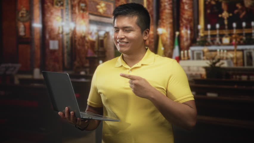 Man in yellow polo typing on laptop with visible hands in ornate church building near altar and candles; contemplation focus.