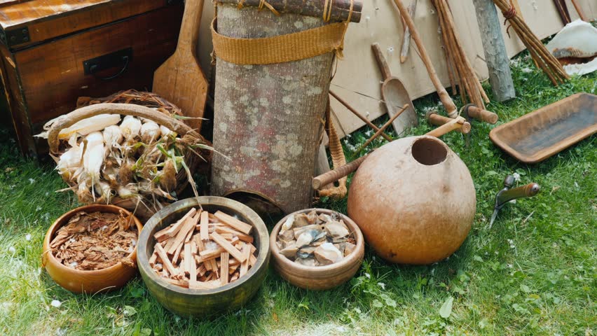 Primitive tools weapons and supplies arranged on grass outdoor display.