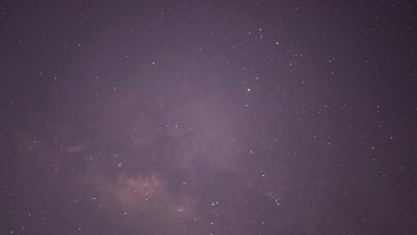 Beautiful timelapse footage of the Milky Way and stars moving across the dark night sky toward early morning light. Atmospheric astrophotography scene with natural cosmic motion.