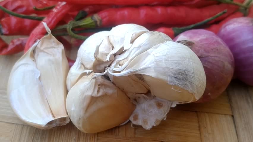 Fresh peeled shallots, garlic cloves, and red chili peppers ready for cooking