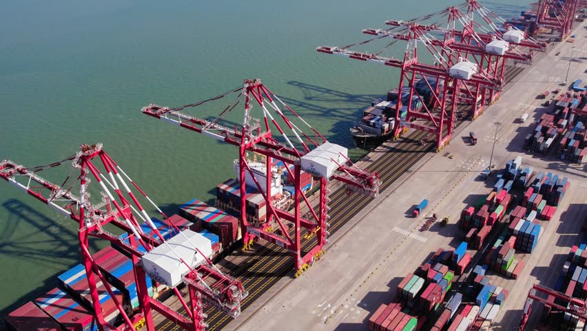 An aerial drone shot of the bustling Guangzhou Port in China, showcasing its massive container terminal, cargo ships, and efficient container handling operations.