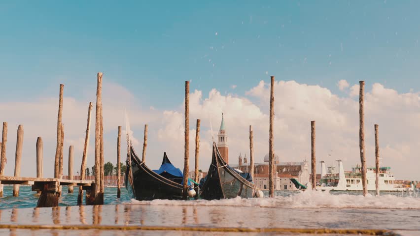 Venice gondolas at pier, water splashing in foreground, italy.