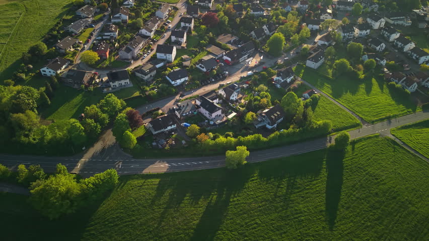 Aerial view of small residential neighborhood surrounded by green countryside in Germany at sunset.