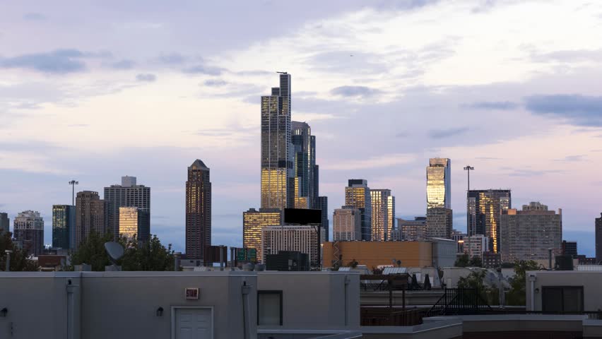 Dramatic day to night transition over Chicago city skyline. Cinematic urban landscape video captures golden hour light hitting buildings followed by evening purple sky and glowing office lights.