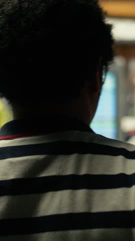 Black commuter gathers near information board in busy city bus station during rush hour, waiting for urban transport commercial services. People in a fast-paced public transportation hub.