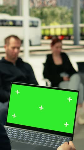 Isolated green screen laptop with seated commuter in modern bus terminal during rush hour. Busy passengers and groups move through urban transit hub, dynamic city travel atmosphere.