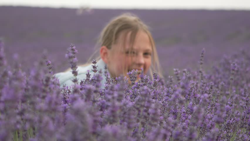 Young girl lavender field. Happy child smiling and playing playfully amidst fragrant purple flowers in nature