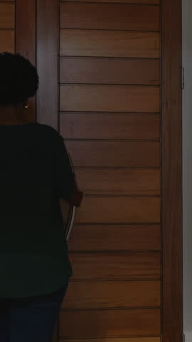Vertical video: Couple greeting, woman opening door as man bringing pink bouquet to give. Flowers, magenta, porch, daylight, romance, pair, vertical video
