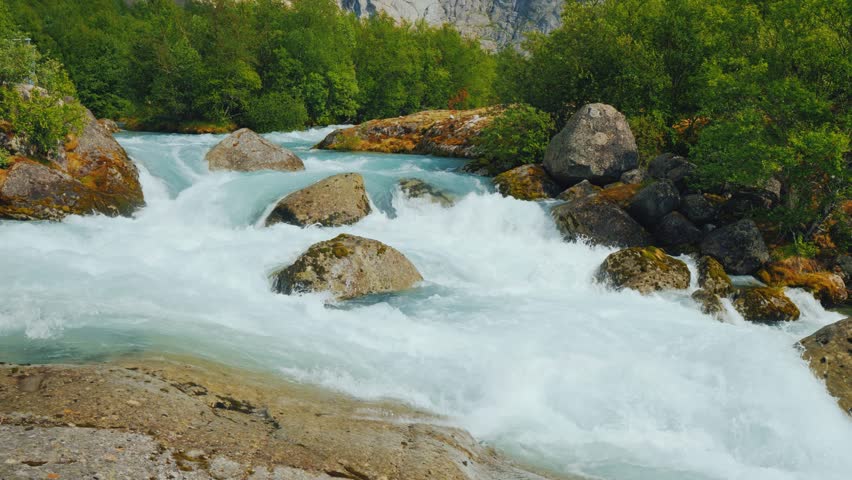Dynamic white water rapids flowing from majestic blue glacier.