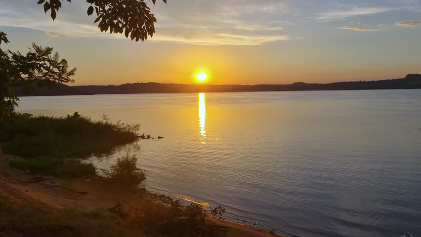 Sunset over Río Paraná near Playa del Sol beach, San Ignacio, Argentina, with Paraguay across the calm river, tropical natural scenery, and serene waterscape