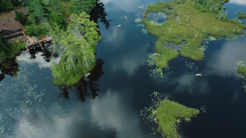 Drone overhead shot following kayakers on Rainbow Lake in the Adirondacks in Upstate New York.