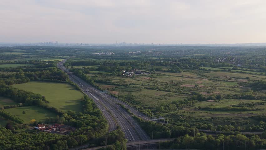 Looking down at a multi-lane highway with moving cars and parallel railway tracks.
