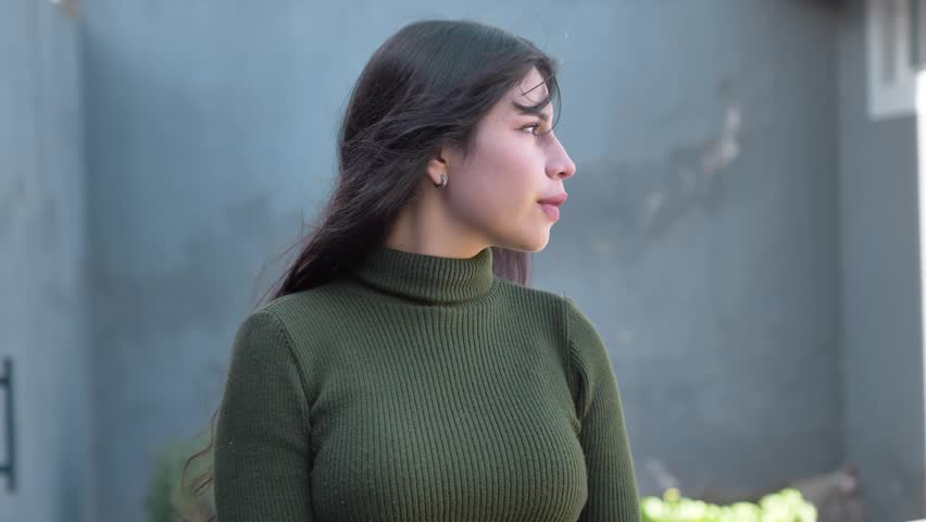 Young brunette woman slowly turns her head and looks toward the camera