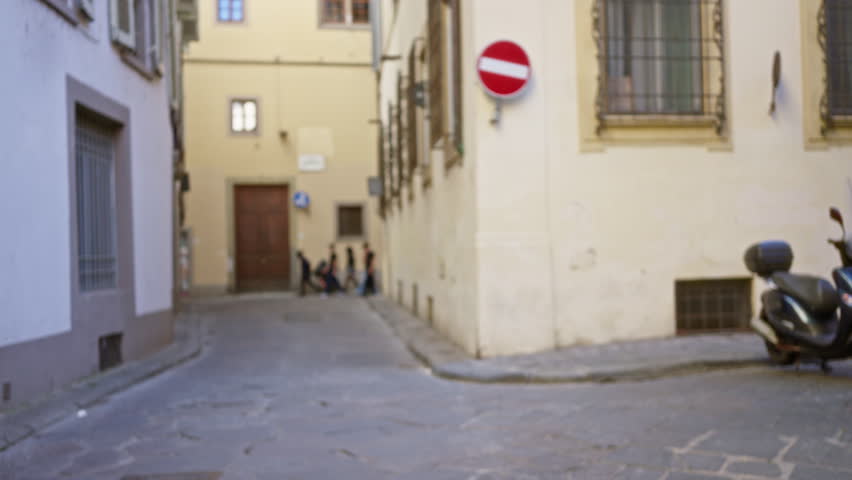 Sunlit narrow florence cobbled street with defocused buildings and parked scooter, empty nopeople foreground in soft bokeh street; background backplate copyspace.