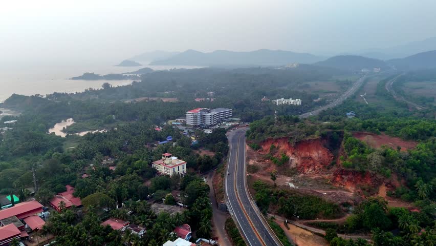 Drone shot capturing a long highway cutting across tropical landscapes, surrounded by palm-covered terrain, open plains, and rolling hills, creating a scenic coastal travel atmosphere.