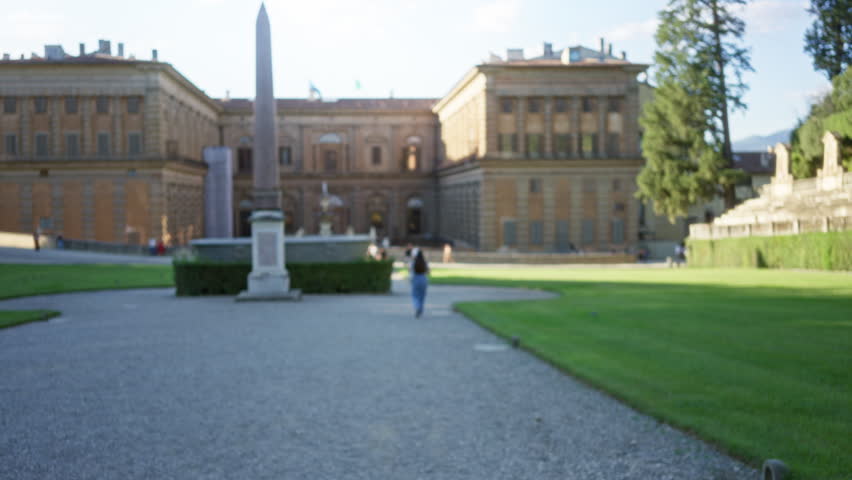 Blurred plaza with shallow bokeh and defocused historic building facade, gravel path and trimmed lawn in soft focus; background backplate copyspace template.