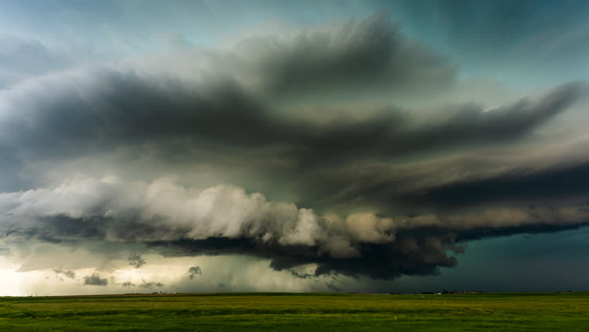 Heavy grey storm clouds sweep across the open landscape, creating a dramatic atmosphere with darkened skies, turbulent motion, shifting weather patterns and the looming threat of incoming rain and strong winds