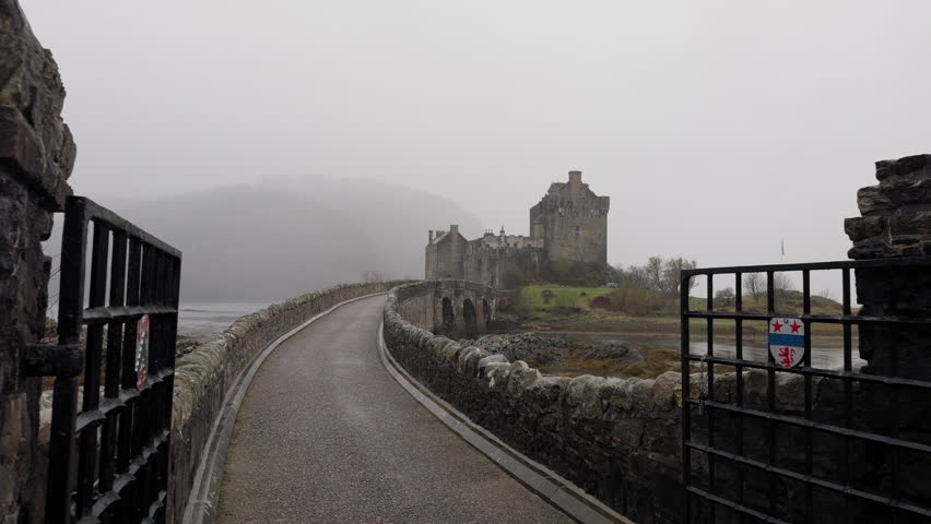 Eilean Donan Castle, Scotland .Panoramic walking shot across the bridge. Cloudy grey skies frame the medieval fortress.