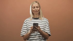 Woman holding smartphone and tapping screen, smiling while checking messages with finger and hands visible in studio; simple joy. - Powered by Shutterstock - Get 15% off with code: PIKWIZARD15