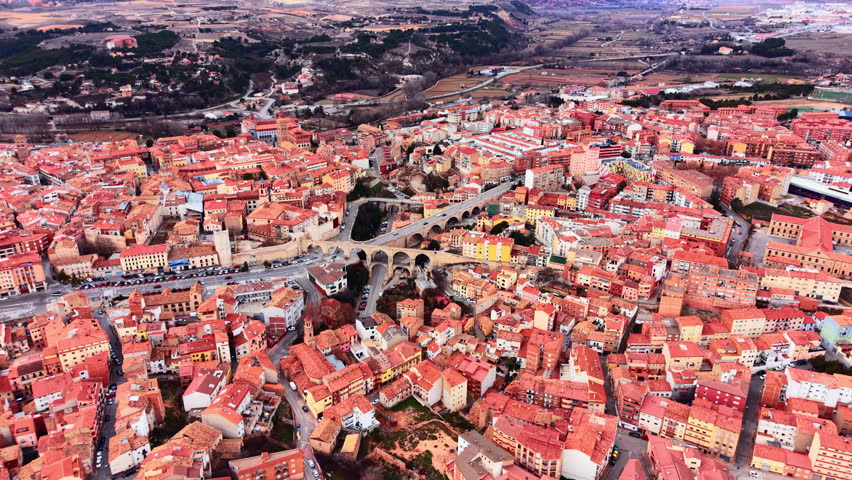 Aerial perspective of Teruel city center featuring traditional architecture, terracotta roofs, and the historic arched stone viaduct crossing a valley.