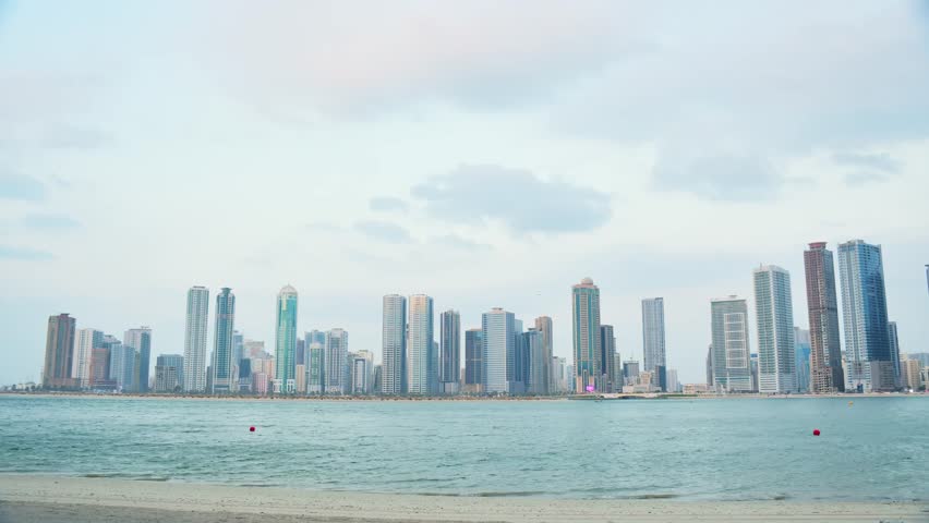 Sharjah Al Khan skyline timelapse UAE. Luxury real estate rental apartments along Al Khalidiyah waterfront. Urban development ad banner. Highrise skyscrapers, beach, Gulf architecture, Middle East.