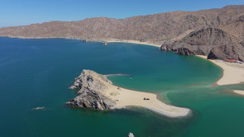 Watch an aerial view of an SUV parked with a teardrop trailer on a remote island in Gonzaga Bay in Baja California, Mexico.