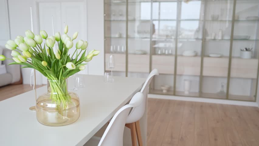 Happy woman setting the table for celebration dinner in the white modern kitchen. Festive table with delicious dishes for family holiday.