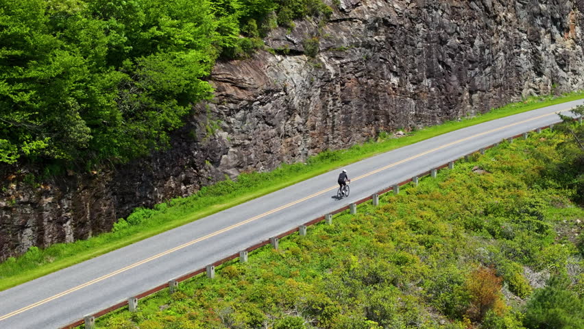 Aerial view of fit cyclist riding along scenic mountain road in Appalachian Mountains. Endurance, adventure and active outdoor lifestyle concept.