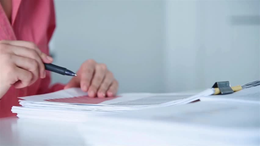 Close-up of hands drawing a geometric cone shape on white paper using a pencil and ruler in a well-lit workspace.