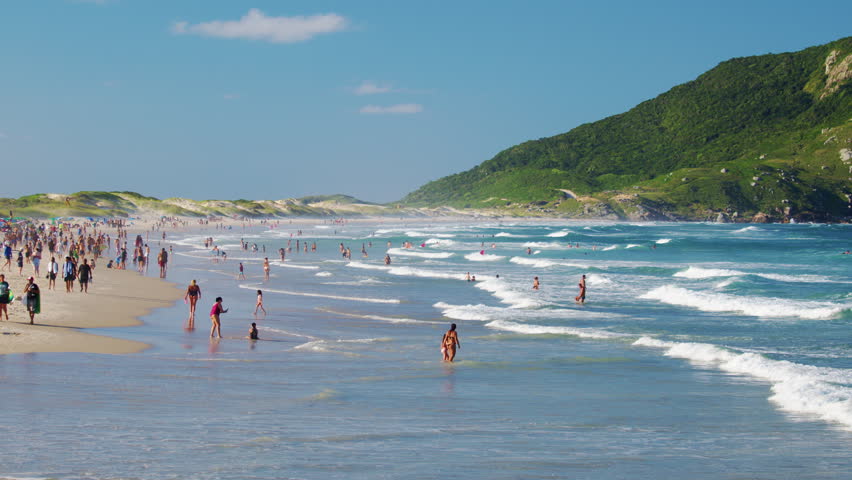Santinho beach with people relaxing near the water. Florianopolis, Brazil